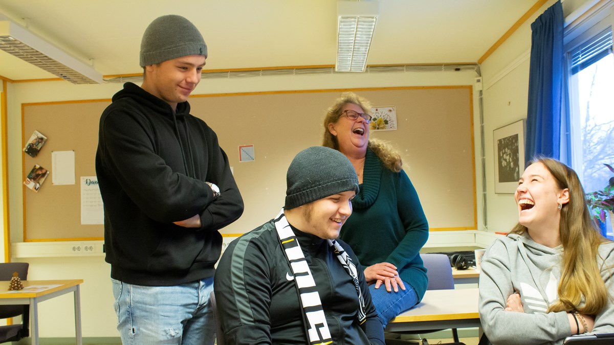 Deltagare tillsammans med lärare som skrattar i ett klassrum